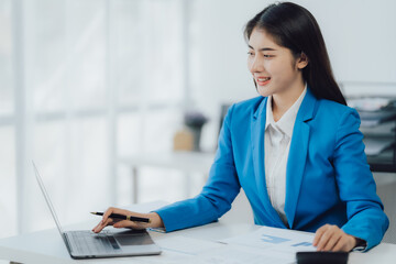 Young charming businesswoman sitting at her desk with laptop computer on the table.