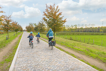 Obraz premium Family bike ride in autumn park. Woman and two children