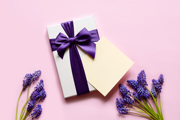 Flat lay composition with muscari flowers, gift box and envelope mockup with blank greeting card on light background. Minimal floral frame. Happy mother's day, women's day, birthday or wedding.