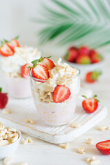 Desserts of cookies and whipped cream with strawberries in glasses, close-up, background in blur.