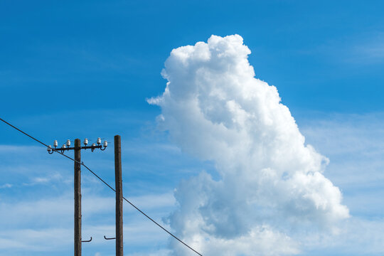 White cloud at the sky, over the old wooden electricity post and wires