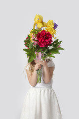Fototapeta premium Studio portrait of beautiful little girl holding big colorful bouquet of various flowers.