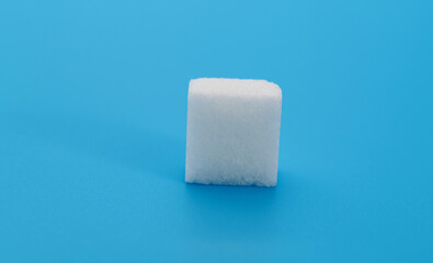 One sugar cube on blue background