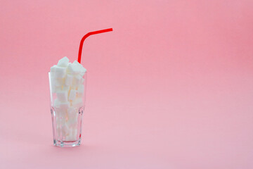 Glass cup full of sugar cubes on pink background