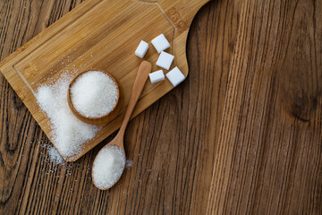 A bowl granulated sugar and sugar cubes on the board