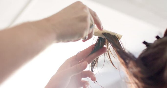 Hands of caucasian male hairdresser combing client's long hair at hair salon, slow motion
