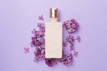 Composition with cosmetic bottle and flowers on color background, top view