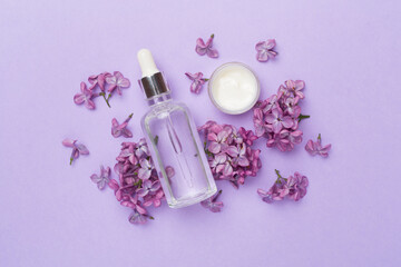 Composition with cosmetic bottle and flowers on color background, top view