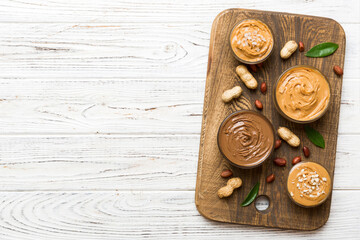 Glass jar with peanut butterin plate on table background, top view space for text and close up