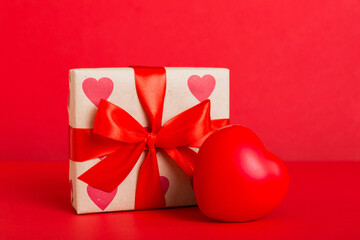 gift box with red bow and red heart on colored background. Perspective view. Flat lay