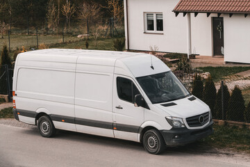 A white delivery van is parked on the side of the road. Door-to-door delivery mockup. Logistics...