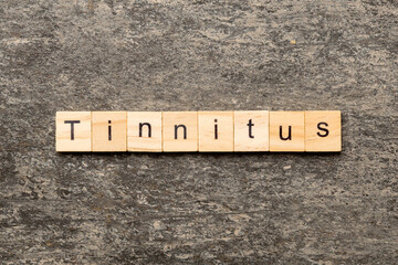 TINNITUS word written on wood block. TINNITUS text on cement table for your desing, concept
