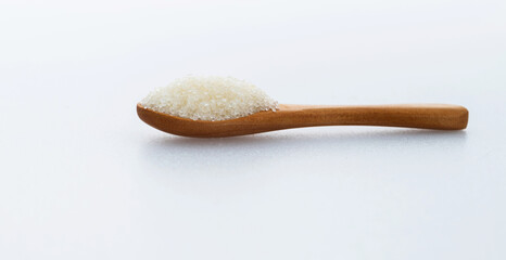 Wooden spoon with sugar crystals on white background