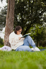 Obraz premium Curvy woman with Down syndrome reading in the park