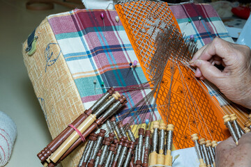 Tradiciones vivas: Habilidosa artesana tejiendo encajes de bolillos con destreza y precisión.