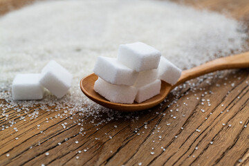 Spoon with sugar cubes on top of granulated sugar