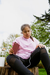 Obraz premium Young curvy girl with Down Syndrome relaxing and listening to music after workout