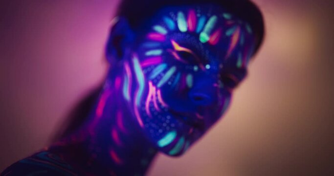 Expressive Female Dancer Transcends Boundaries with Contemporary Dance. Cinematic Close Up Portrait of a Young Creative Performer in Neon Body Paint, Looking at Camera, Moving in Improvised Fashion