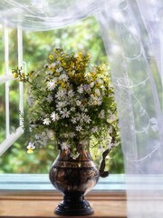 Still life with bouquet of wildflowers on a windowsill