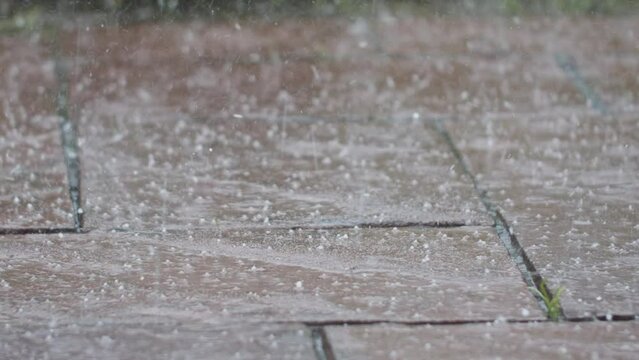Slow-motion shot of hail hitting some old flagstones. Handheld camera shot with shallow depth of field.