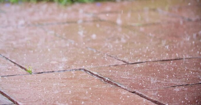 Wide shot of hail hitting terrace stones. Handheld shot with shallow depth of field.