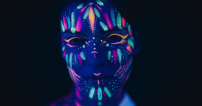 Innovative Beauty Advertising Shoot: Talented Model Showcases Her Unique Style, Neon-Painted Body and Face Contrasting Beautifully with Dark Backdrop, Creating a Visually Stunning Close Up Portrait