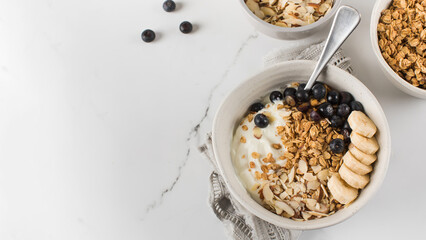 Homemade granola with Greek yogurt, almonds, blueberries and banana in a bowl. Copy space