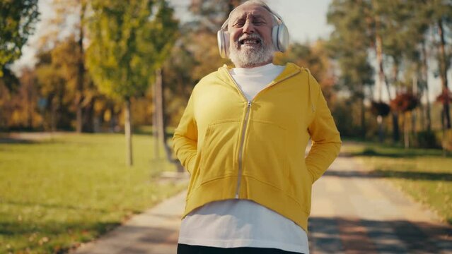 Senior man suffering lower back pain while jogging in a park, sports injury