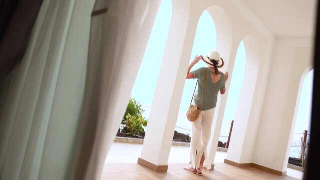 Elegant lady wearing sunhat arriving Mediterranean luxury hotel 