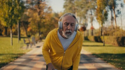 Senior man feeling breathless during jog in park, making stop to catch a breath