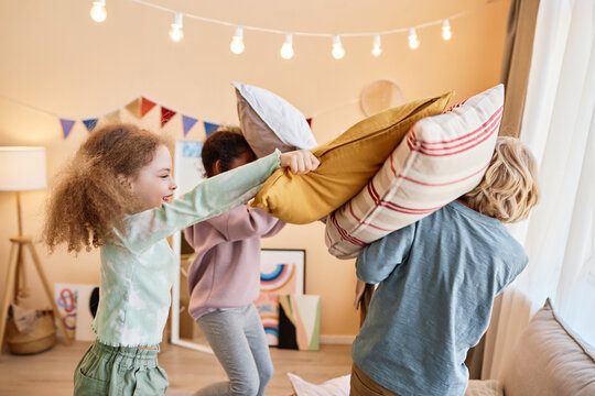 Diverse group of little children enjoying pillow fight and having fun playing together