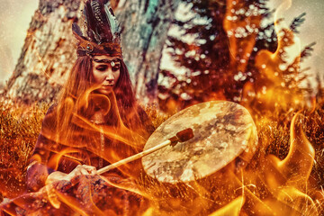 beautiful shamanic girl playing on shaman frame drum in the nature. Fire background.