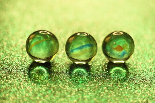 Three glass balls on glitter green table