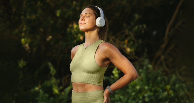 Woman listening to music and doing a breathing exercise outdoors