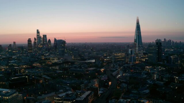 Slow establishing circling aerial shot of Central London skyscrapers at dawn