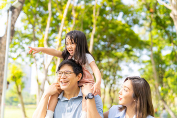 Fototapeta premium Happy Asian family spending time together travel on summer holiday vacation. Parent and little child enjoy and fun outdoor activity lifestyle walking and playing together at public park in the city. 