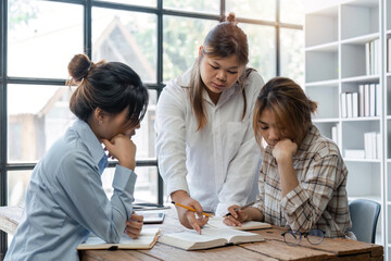Distracted from preparing college project happy young laughing diverse classmates having fun, telling jokes, enjoying carefree pause time together, sitting at table in library