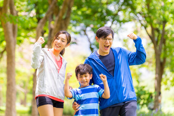 Portrait of Happy Asian parent and little kids enjoy outdoor lifestyle on summer vacation. Father, mother and child exercising and playing together at park. Family relationship and health care concept