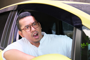 Adult Asian man showing furious expression when driving his car