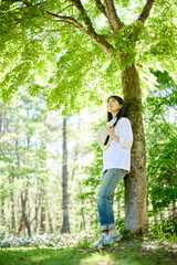 Naklejka na ściany i meble 森の中でリラックスしながら森林浴を楽しむ30代日本人女性の初夏のイメージ