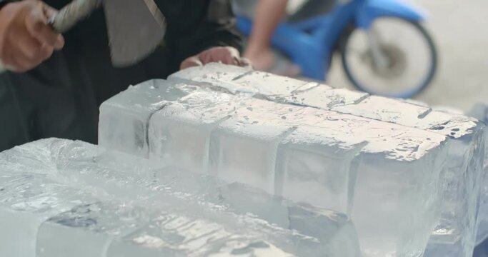 A large chunk of ice was cut with an axe.Close up hand cut ice.A man cut the ice into smaller cubes and crush them finely.	