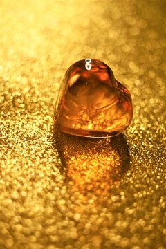 Amber glass heart on shiny golden table
