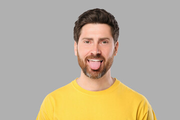 Obraz premium Man showing his tongue on gray background