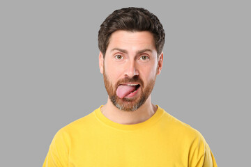 Obraz premium Man showing his tongue on gray background