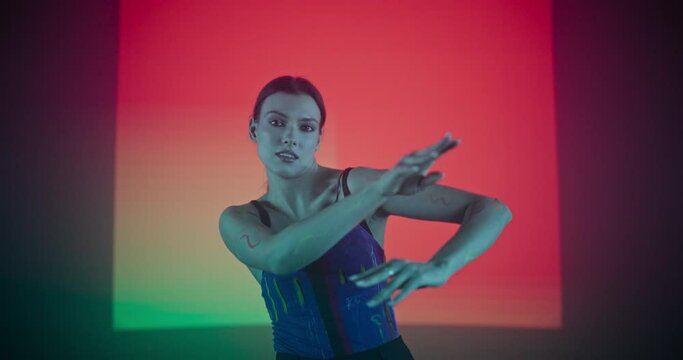 Portrait of a Talented Female Artist Showcasing Graceful Movements and Expressive Emotions with Her Innovative Modern Dance Routine in a Dark Studio with Color Changing Background
