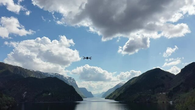 Drone flies into frame, adjusts position for shooting footage of Norway fjord.