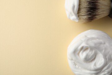 Brush and shaving foam on beige background, flat lay. Space for text