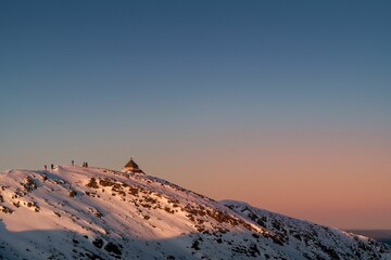 Beautiful shot of a small church at the mountain covered in snow at sunset