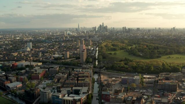 Dolly back aerial shot over Hertford union canal and Victoria Park with central London skyline