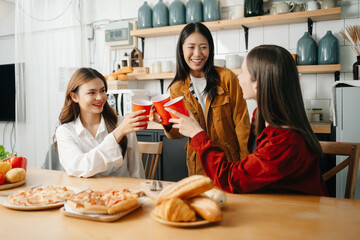 Group of friends making fun at home party.They sitting on desk in living room and eating pizza. happy